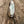 Load image into Gallery viewer, A feather bass fishing spoon with a treble hook attached with a split-ring, laying flat on a plank of grey and brown weathered wood.
