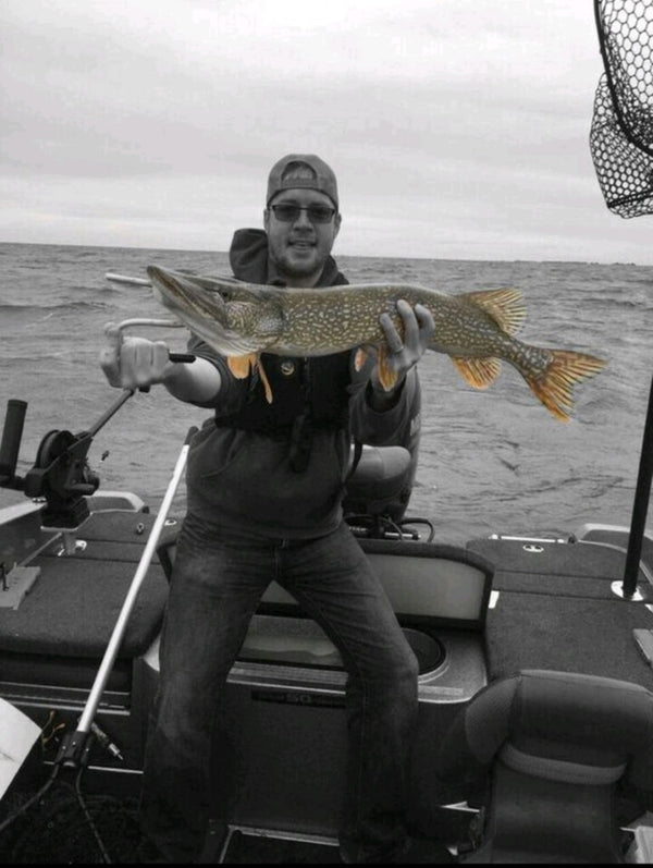 Michael Hiller fishing, holding a pike from a boat.