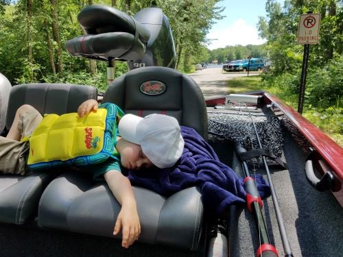 A young Levi Hiller sleeping in a trailered bass boat.