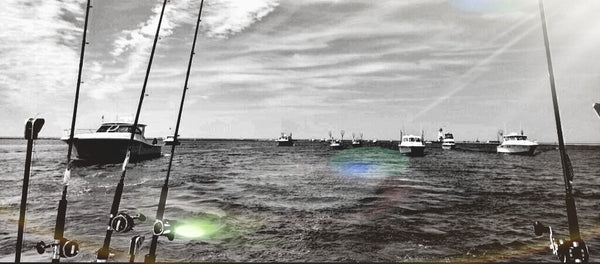 A view from the back of a fishing boat of a pack of sportfishing boats following it on open water.