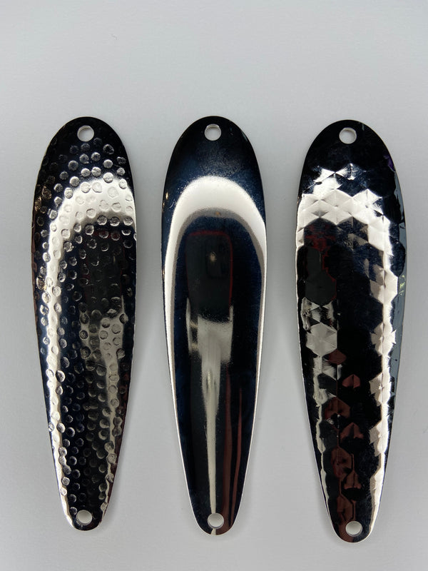 Three fishing spoons orientated vertically. All three spoons blanks that are nickel-plated and shiny.  The left lure has a hammered finish. The center lure has a smooth finish. The right most lure has a hex style finish.
