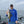Load image into Gallery viewer, Mike Hiller wearing a baseball hat, sunglasses, and blue hoodie, standing in a boat on open water using a Gill Cleat to hold a small mouth bass. The fish has a pink fishing spoon in it&#39;s mouth. There are nets and fishing poles in the background.
