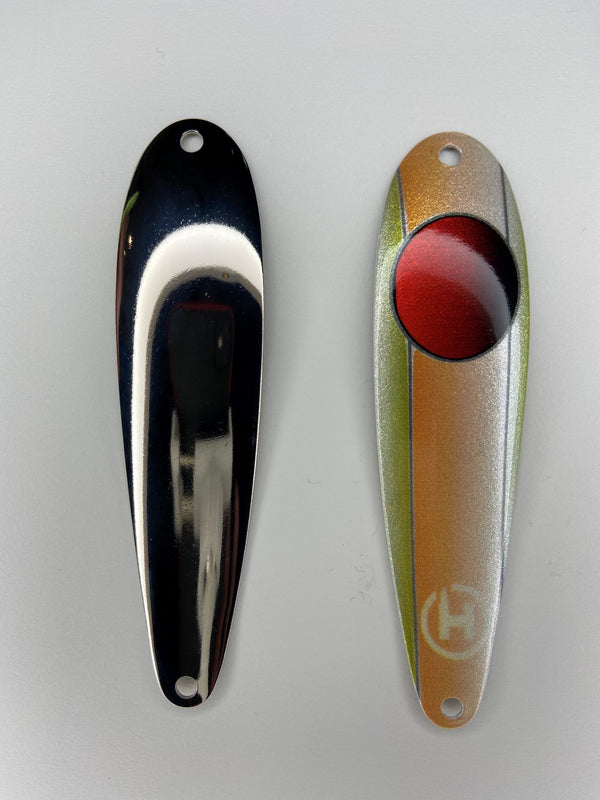 On the right there is an orange and olive bass fishing lure with a red circle that fades to black near the top with a small white HangryBrand logo near the bottom. On the left there is a shiny hex style, bass fishing spoon. that is nickel-plated.