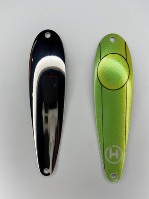 Two fishing lures. A custom brown trout fishing spoon that is lime green and chartreuse with a small, white HangryBrand logo near the bottom. On the lure are thin, black lines that run down its length. Also, an outline of a large circle. Another fishing spoon that is smooth and shiny for brown trout fishing.