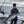 Load image into Gallery viewer, Victor Froman holding a salmon fish while standing in a boat with down riggers and Lake Michigan in the background.
