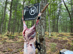 A skinned whitetail deer hanging from a cool looking gambrel that is also an oversized cutting board. A deer ready to be quartered and processed in Northern LowerMichigan.