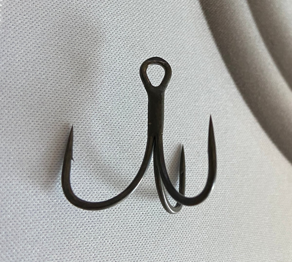 A barbed treble hook dark grey in color.