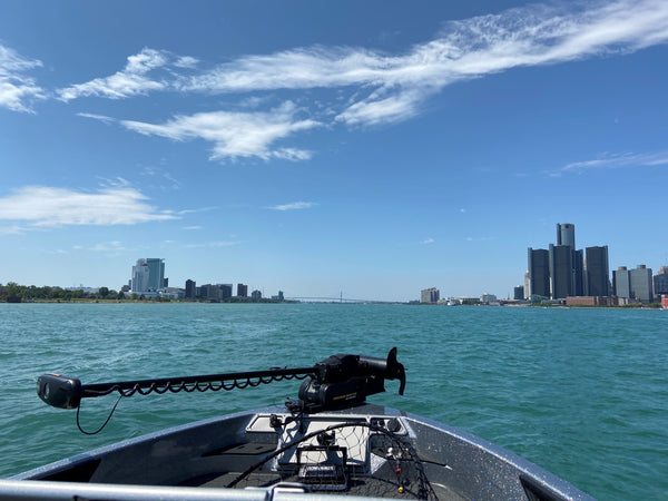 trolling motor mounted to the bow of a boat that faces the Detroit city skyline and the Ambassador bridge on the Detroit river.