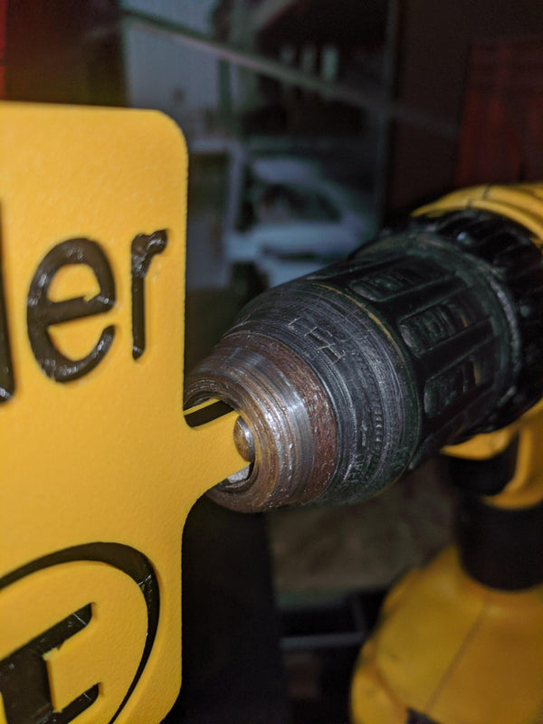 A yellow and black, cordless drill motor with a yellow and black fishing line stripping tool attached.