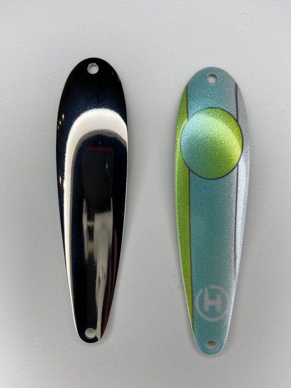 Two fishing lures. A custom brown trout fishing spoon with a Baby blue stripe down the center that fades to pearl white with one side that is chartreuse and one side that is pearl white.  This spoon has a baby blue circle near the top that fades to chartreuse, also there is a small, white HangryBrand logo near the bottom. Another fishing spoon that is hammered and shiny for brown trout fishing.