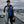 Load image into Gallery viewer, Victor Froman holding a big steelhead fish while standing in a boat with rod holders and Lake Michigan in the background.
