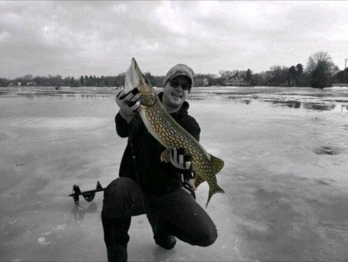 Michael Hiller ice fishing, holding a pike.